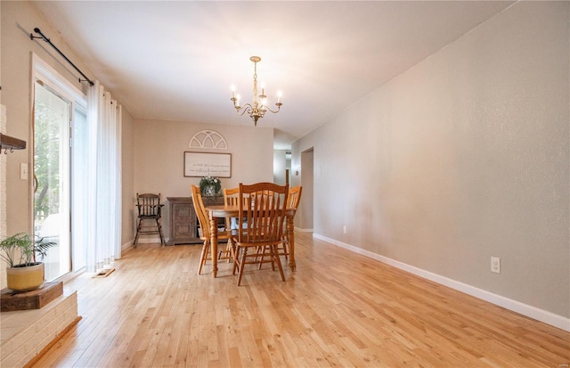 dining area with light hardwood / wood-style floors and a notable chandelier