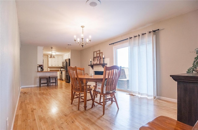 dining space with a notable chandelier and light hardwood / wood-style flooring