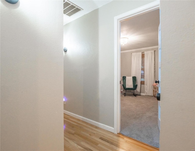 hallway featuring ornamental molding and light hardwood / wood-style floors