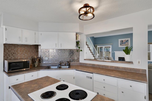 kitchen featuring dark countertops, stainless steel microwave, stove, white dishwasher, and a sink