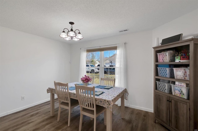 dining room featuring an inviting chandelier, a textured ceiling, visible vents, and dark wood-style flooring