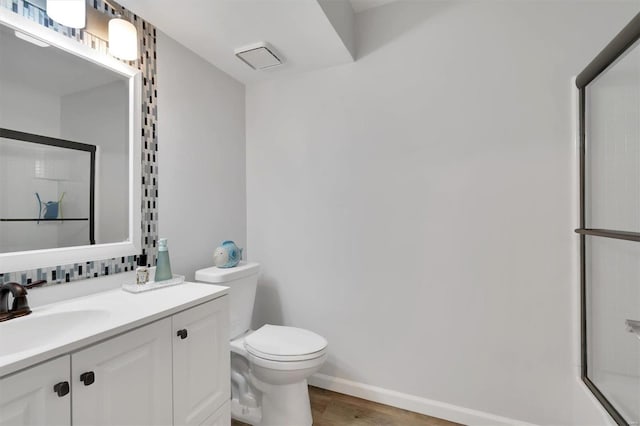 bathroom featuring a shower with door, vanity, toilet, and wood finished floors