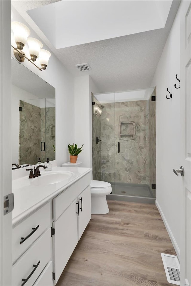 bathroom featuring vanity, a marble finish shower, wood finished floors, and visible vents