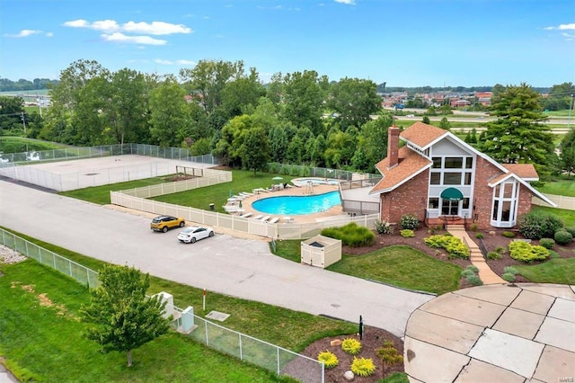 community pool with a lawn, a patio area, and fence