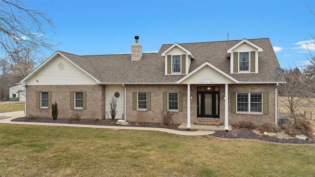 new england style home featuring a front yard, a chimney, brick siding, and a shingled roof