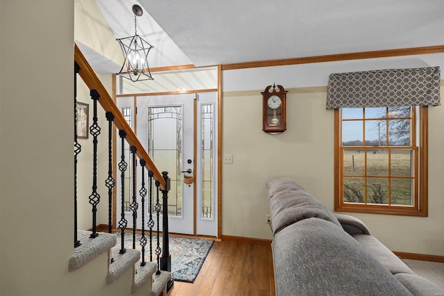 foyer with a notable chandelier, hardwood / wood-style flooring, a textured ceiling, stairway, and baseboards