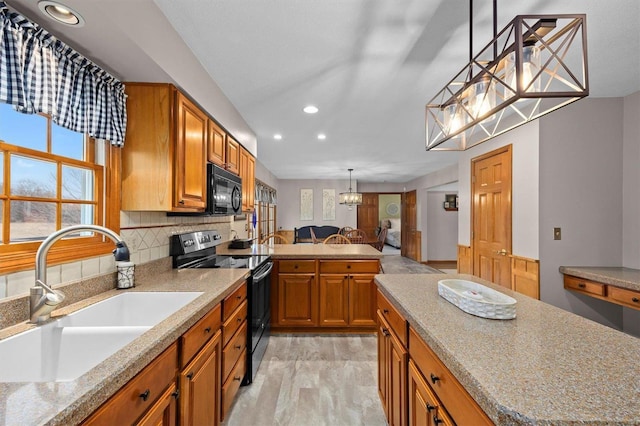 kitchen with brown cabinetry, a sink, black appliances, pendant lighting, and backsplash