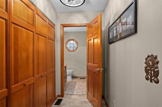 corridor featuring visible vents, wallpapered walls, and baseboards