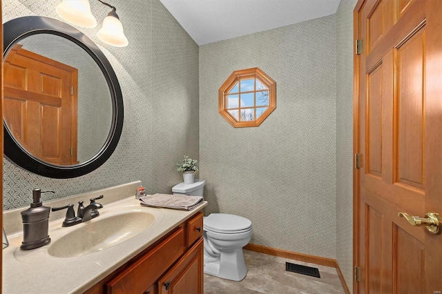 bathroom featuring visible vents, toilet, wallpapered walls, and vanity