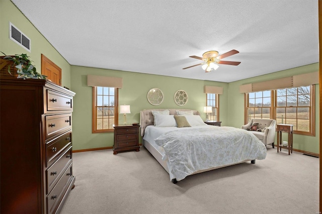 bedroom with visible vents, baseboards, light colored carpet, and a textured ceiling