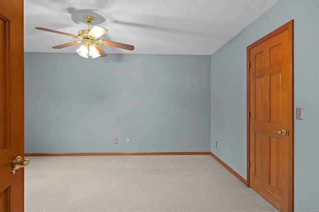 empty room with light colored carpet, a textured ceiling, baseboards, and ceiling fan