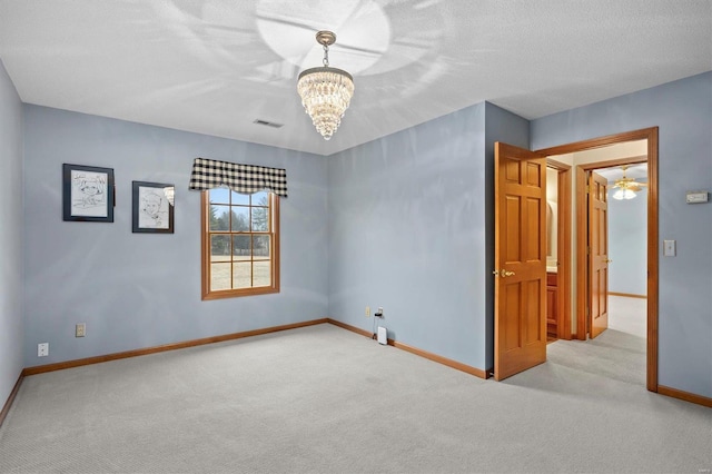 unfurnished room with an inviting chandelier, baseboards, visible vents, and carpet floors