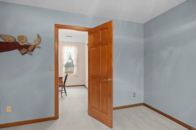 interior space featuring baseboards, light carpet, and a textured ceiling