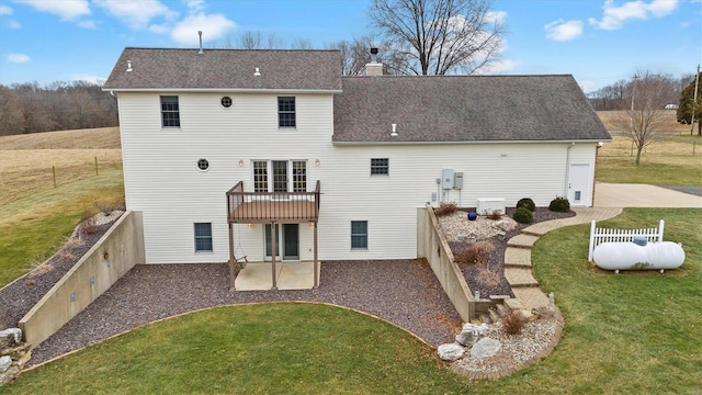 rear view of house with a fenced backyard, a shingled roof, a chimney, a patio area, and a lawn