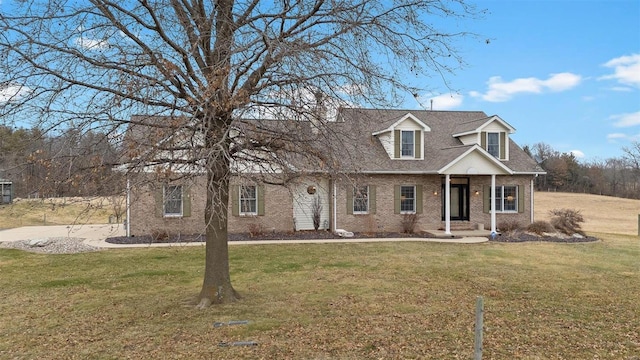 cape cod-style house with brick siding, roof with shingles, and a front yard