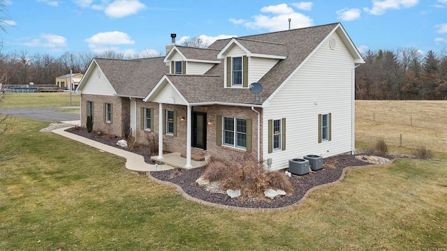 view of front of home featuring cooling unit, a front yard, and roof with shingles