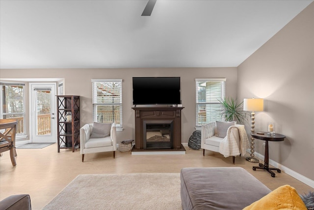 living room with lofted ceiling, a glass covered fireplace, a wealth of natural light, and baseboards