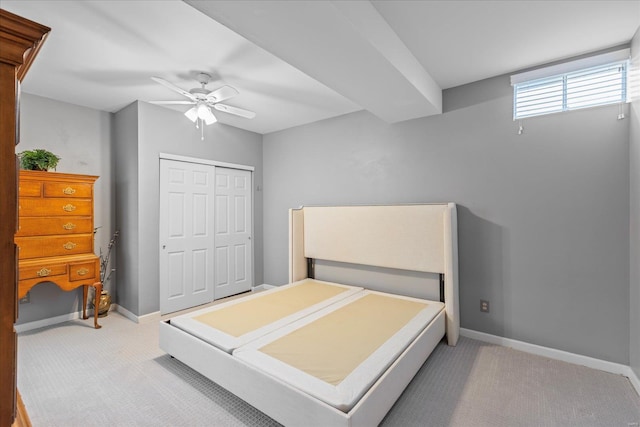 bedroom featuring light carpet, ceiling fan, baseboards, and a closet