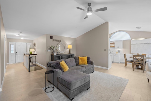 living area featuring light wood finished floors, baseboards, visible vents, ceiling fan, and vaulted ceiling