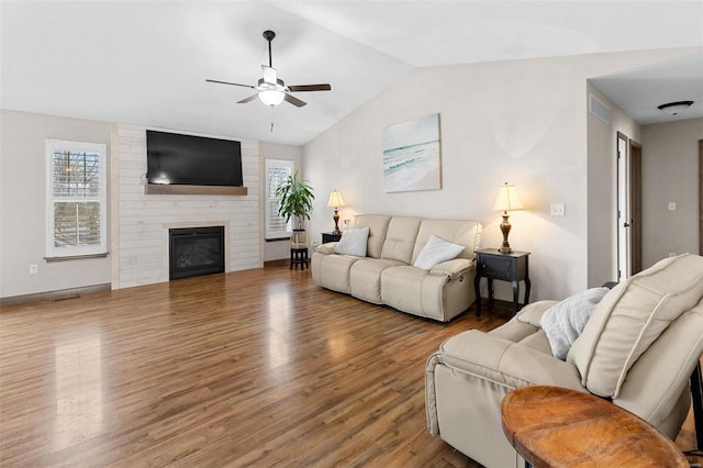 living room with wood-type flooring, plenty of natural light, lofted ceiling, and a fireplace