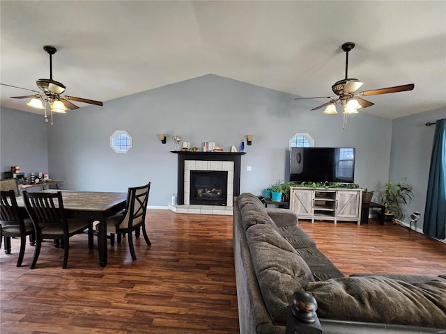 living room with a tiled fireplace, dark wood-type flooring, and ceiling fan