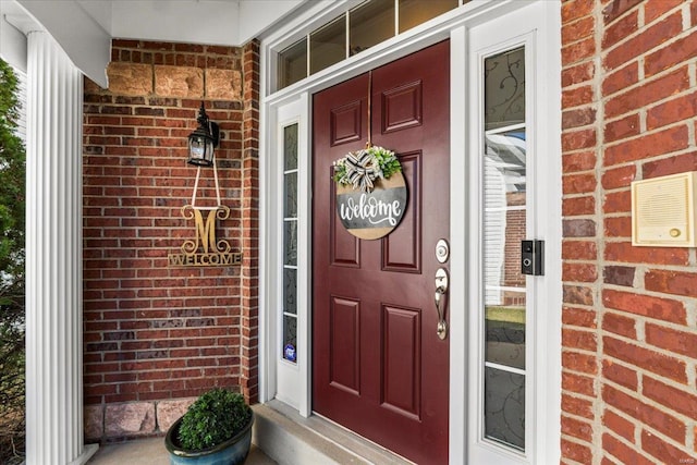 doorway to property featuring brick siding and a porch