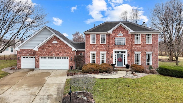 colonial inspired home with a garage, driveway, a chimney, a front yard, and brick siding