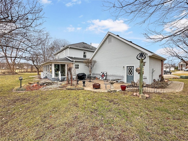 rear view of property featuring a sunroom, an outdoor fire pit, a patio area, and a lawn