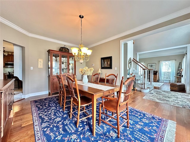 dining space featuring crown molding, stairway, wood finished floors, a chandelier, and baseboards