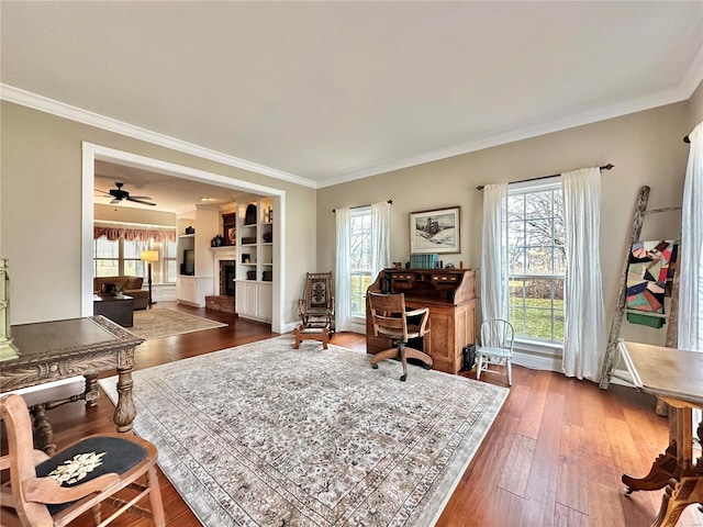 interior space featuring dark wood-style floors, ceiling fan, a fireplace, and crown molding