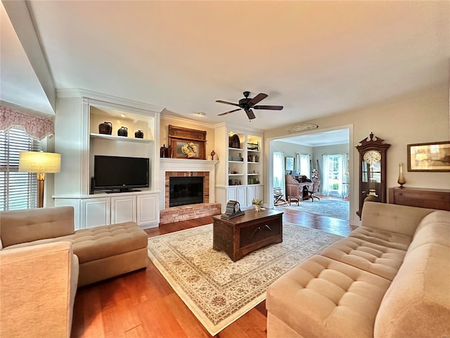 living room with built in features, a fireplace, and wood finished floors