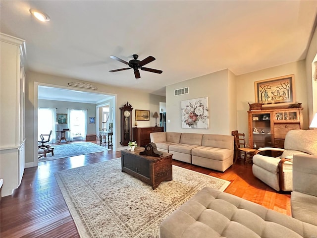 living area with a ceiling fan, baseboards, visible vents, and wood finished floors