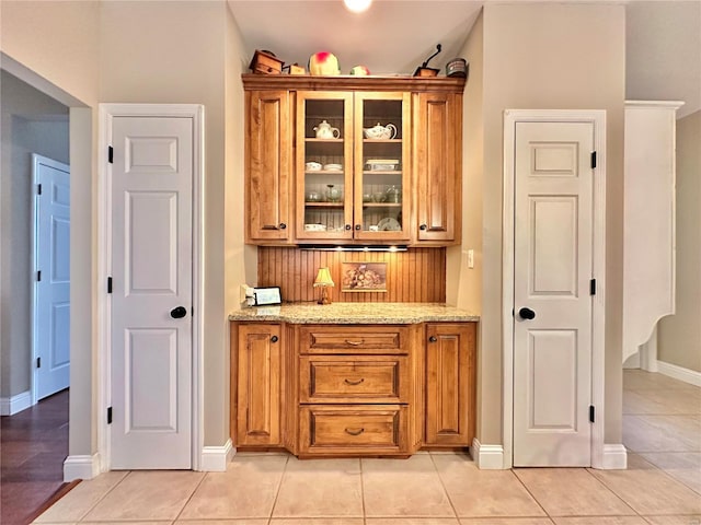 bar with light tile patterned floors, baseboards, and backsplash