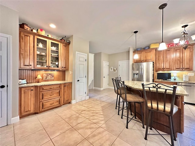 kitchen with appliances with stainless steel finishes, brown cabinets, and light stone counters