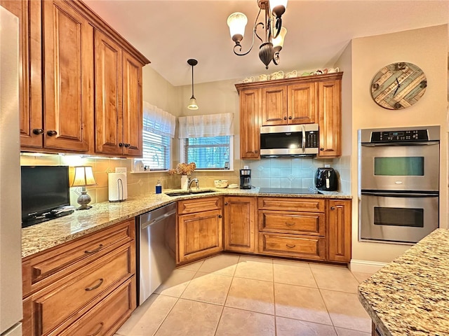 kitchen with tasteful backsplash, appliances with stainless steel finishes, a sink, and brown cabinets