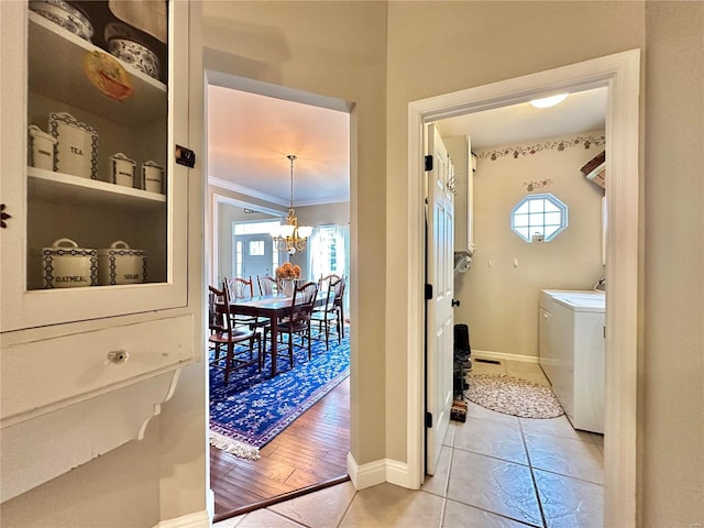 interior space featuring crown molding, baseboards, a chandelier, and washer and dryer