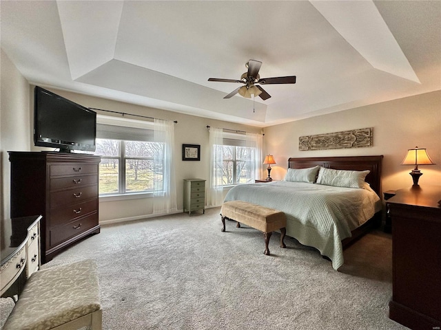 bedroom with a ceiling fan, a raised ceiling, light carpet, and baseboards