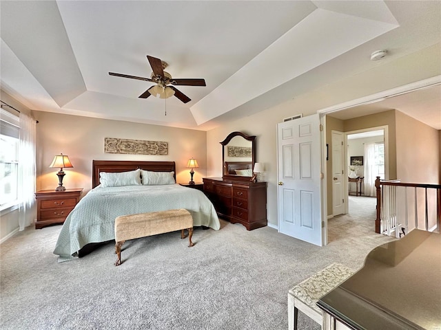 carpeted bedroom with a tray ceiling, ceiling fan, and baseboards