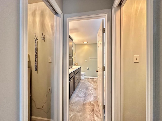 interior space with vanity, toilet, and baseboards