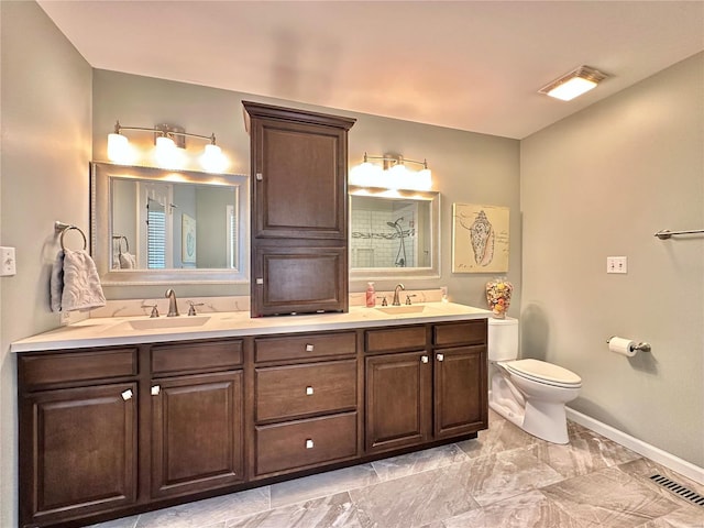 bathroom with toilet, double vanity, visible vents, and a sink