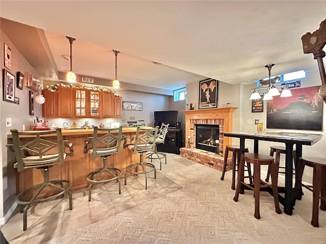 kitchen with brown cabinets, a fireplace, glass insert cabinets, a peninsula, and a kitchen bar