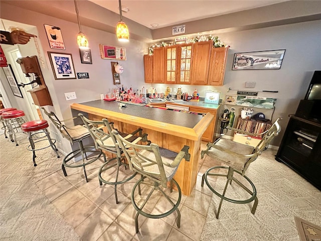 kitchen with a breakfast bar, pendant lighting, glass insert cabinets, brown cabinetry, and a peninsula