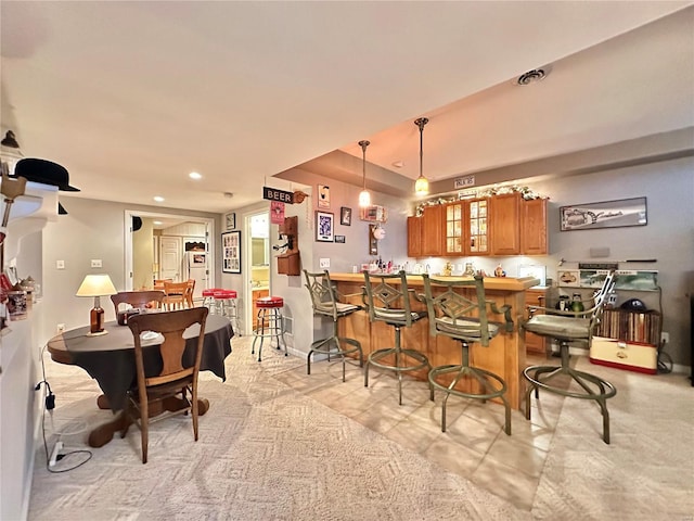 kitchen featuring brown cabinetry, decorative light fixtures, a peninsula, a kitchen bar, and recessed lighting