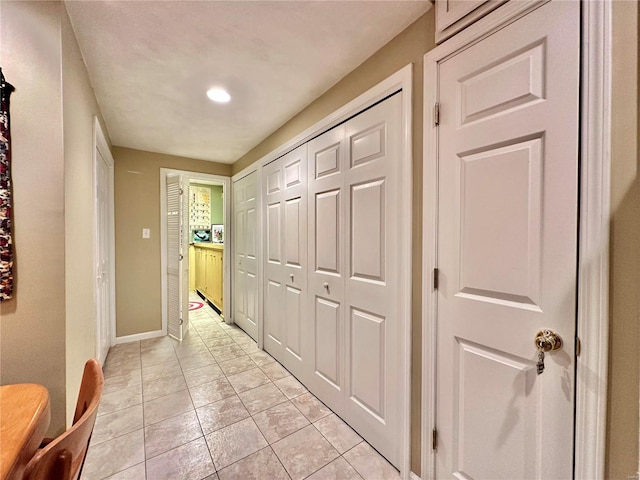 hallway featuring light tile patterned floors and baseboards