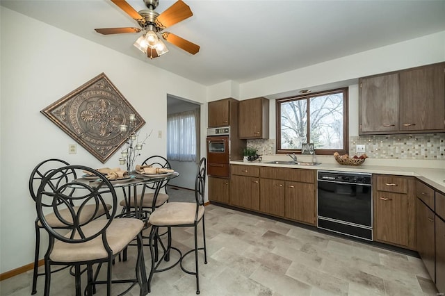 kitchen featuring backsplash, light countertops, black dishwasher, a warming drawer, and a sink