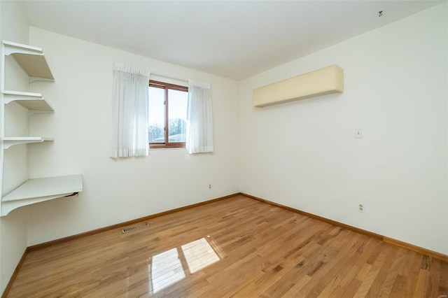 unfurnished room featuring light wood-style floors, visible vents, and baseboards