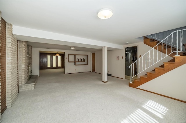 finished basement with stairway, carpet, brick wall, a fireplace, and baseboards