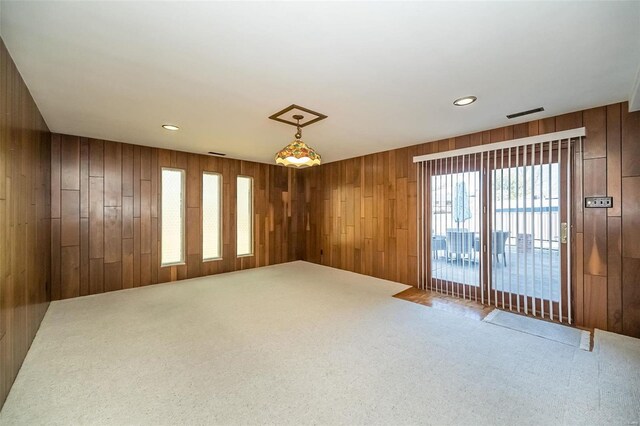 carpeted empty room featuring recessed lighting, wood walls, and visible vents