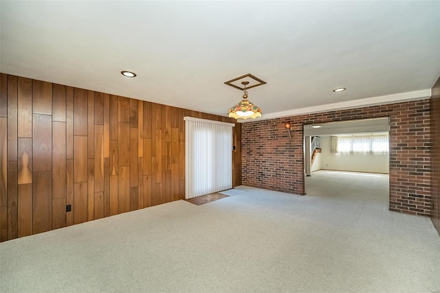 spare room with brick wall, recessed lighting, wood walls, and carpet floors