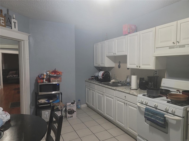 kitchen featuring white gas range, a textured ceiling, white cabinets, and light tile patterned flooring